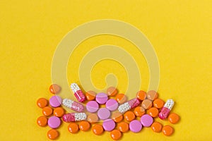 Multi-colored pills on a bright yellow background, top view. Medication for the disease for patients. Dose drugs and vitamins for