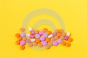Multi-colored pills on a bright yellow background, top view. Medication for the disease for patients. Drugs and vitamins for healt
