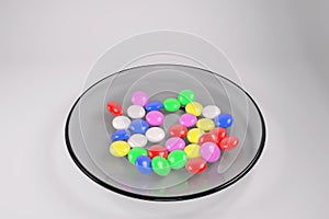 Multi-colored pills in a glass plate. 3D rendering