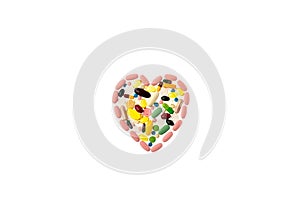 Multi-colored pills in the shape of heart in the center of white isolated background. Daily Vitamins dose. Heart shape