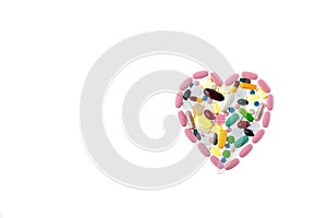 Multi-colored pills in the shape of heart on a white isolated background. Daily Vitamins dose. Heart shape made of