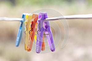 Multi colored plastic clothes clips on the wire on nature background.