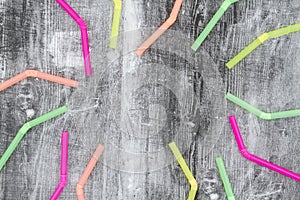 Multi colored plastic straws on black grunge background
