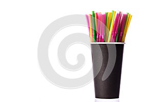 Multi-colored plastic straws in black paper glass isolated on white background