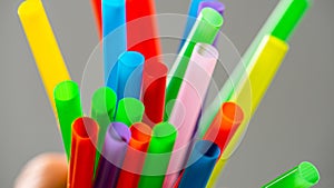 Multi colored plastic straws in a jar in front of a grey background...