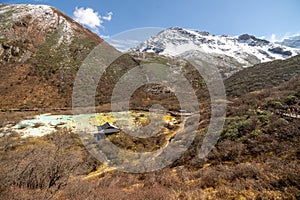 Multi-Colored Pond and Temple Against a Snow-Capped Mountain Backdrop in Huanglong, China