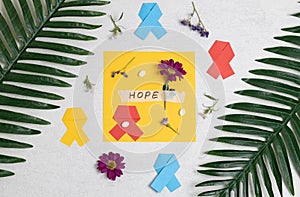 Multi-colored ribbons, gerberas, the word hope and pills on a stone.