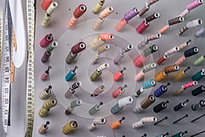 Multi-colored sewing threads, in large quantities, in the sewing workshop, at an unusual viewing angle. Abstract background from