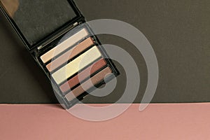 Multi-colored shadows for the make-up stand on a pink table and propped up to a black wall