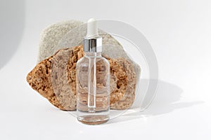 Multi-colored stones with a transparent bottle with a pipette on a white background.