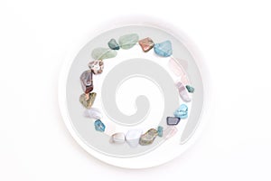 multi-colored stones on a white plate on a white background. place for your text,
