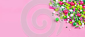 Multi-colored Sugar sprinkle dots, decoration for cake and bekery in pink background. Easter. Copy space. Panorama