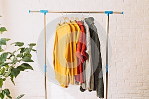 Multi-colored sweatshirts on wooden hangers hang on an iron rack rale photo
