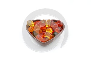 multi-colored sweet candies in heart shaped bowl on white background, top view. Space for text