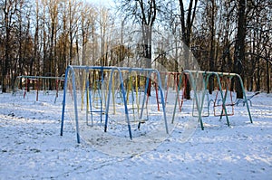 Multi-colored swing in winter time and lit with the evening sun