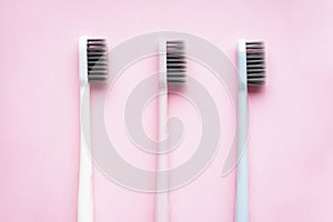 Multi-colored toothbrushes on a pink background close-up, flat lay composition