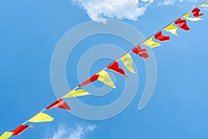 Multi colored triangular flags develop on the background of blue sky. Colorful fairground flags