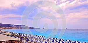 Multi Colored umbrellas on the beach in Nice and turquoise calm water on the Cote d`Azur, France. Sunset at sea photo