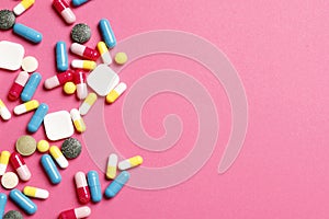 Multi-colored vitamins on a pink background