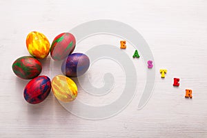 Multi-colored wooden letters making up the words happy easter and decorative colourful eggs on a white background.