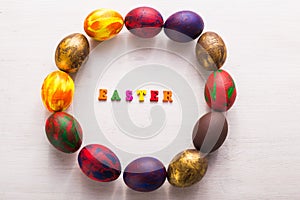 Multi-colored wooden letters making up the words happy easter and decorative colourful eggs on a white background with