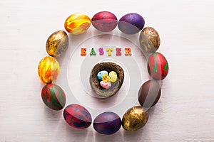 Multi-colored wooden letters making up the words happy easter and decorative colourful eggs on a white background with