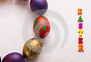 Multi-colored wooden letters making up the words happy easter and decorative colourful eggs on a white background with