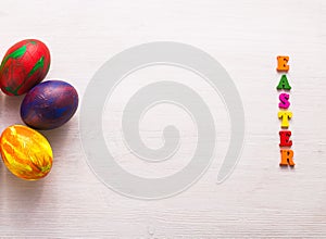 Multi-colored wooden letters making up the words happy easter and decorative colourful eggs on a white background with