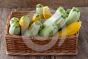 Multi-colored zucchini yellow, green, white, orange on the wooden table close-up. Food background. Fresh harvested