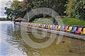 Multi coloured Muskoka Chairs in the lake front of the tourist resort with the patio gazebo