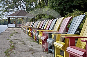 Multi-coloured Muskoka Chairs in the lakefront of the tourist resort with the patio gazebo