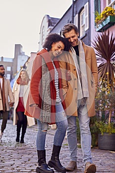 Multi Cultural Couple With Friends Walking Along Residential City Street In Fall Or Winter