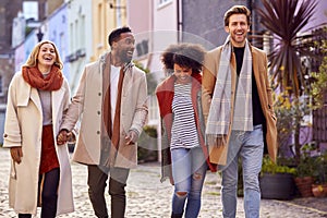 Multi Cultural Couple With Friends Walking Along Residential City Street In Fall Or Winter