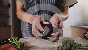 Multi-cultural female cutting an avocado over wooden chopping board full of fresh and healthy vegetables