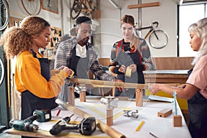 Multi-Cultural Team In Workshop Assembling Hand Built Sustainable Bamboo Bicycle Frame photo