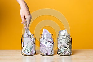 Multi-currency accounts, concept. Dollars and euros in a glass jar on a bright yellow background.