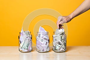 Multi-currency accounts, concept. Dollars and euros in a glass jar on a bright yellow background.