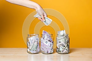 Multi-currency accounts, concept. Dollars and euros in a glass jar on a bright yellow background