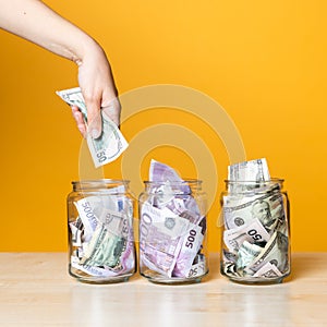 Multi-currency accounts, concept. Dollars and euros in a glass jar on a bright yellow background