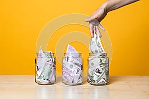Multi-currency accounts, concept. Dollars and euros in a glass jar on a bright yellow background
