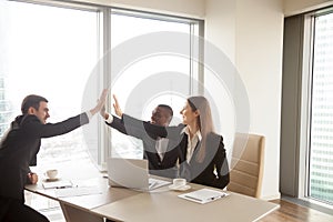 Multi-ethnic business partners giving high five on meeting, cele