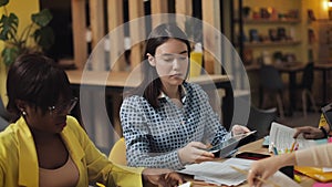 Multi-ethnic business people working and communicating while sitting at the office desk together. Full concentration at