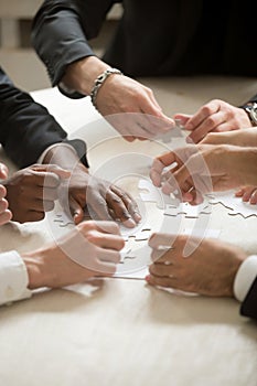 Multi-ethnic business team assembling jigsaw puzzle together, ve