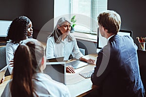 Multi ethnic business team with computers at meeting. Hands of business people touching screen of electronic device