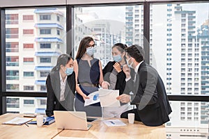 Multi ethnic business team wearing face mask meeting and discussing of business plan in new normal office