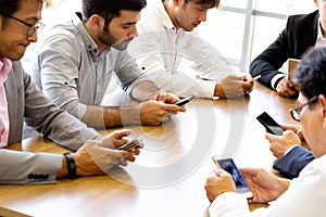 Multi-ethnic businessmen all using phones on desk