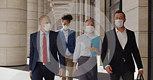 Multi ethnic businessmen and businesswoman walking down street at business center in medical masks