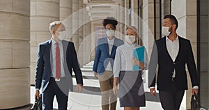 Multi ethnic businessmen and businesswoman walking down street at business center in medical masks