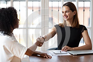 Multiethnic businesswomen greeting each other shaking hands starting business negotiations photo