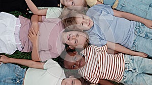 Multi ethnic children lying head to head on schoolyard